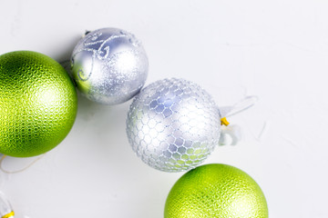 Nice christmas balls in silver and green colors on  white texture surface.