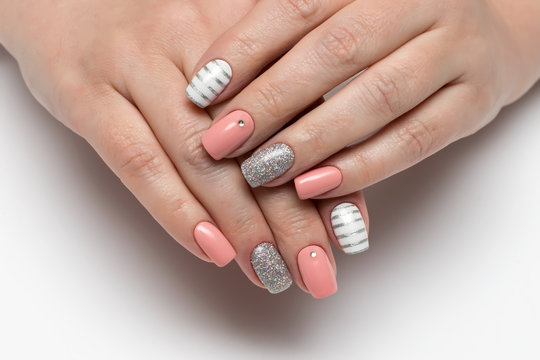 Pink, beige white manicure with silver stripes, crystals, silver glitters on short square nails on a white background close-up
