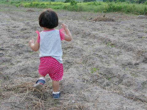 Little Asian Baby Girl, 18 Months Old, Walking Over Uneven Ground In An Open Field - Toddler Gross Motor Skill Development