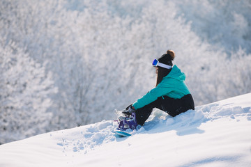 Fototapeta na wymiar Woman snowboarder sitting on high hill and rest