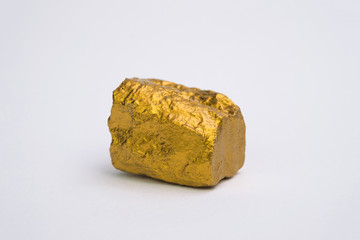 Closeup of gold nugget or gold ore isolated on white background, precious stone or lump of golden stone, financial and business concept.