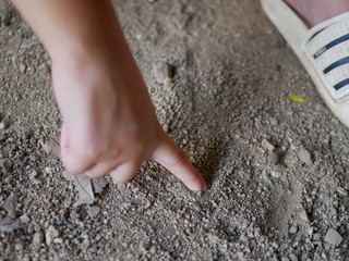 Close up of baby hand drawing on a sandy ground
