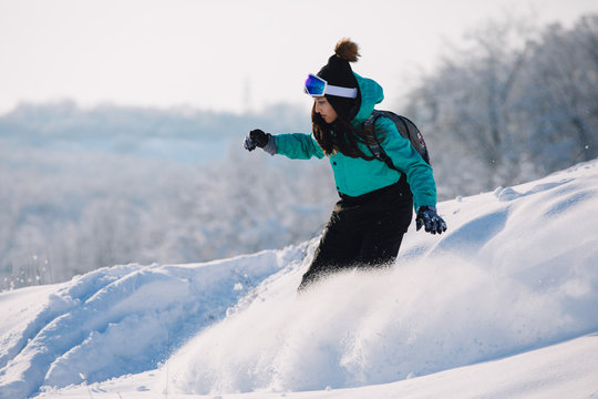 Woman snowboarder riding down from snowy hill