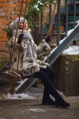 young woman  on  swing in  old courtyard in winter day
