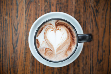 Closeup one coffee cup of hot black cappuccino on clean wooden table in morning light. space for text design. Aroma love caffeine smell.