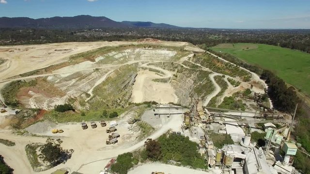 Slow aerial descend over decommissioned limestone mine factory and quarry pit