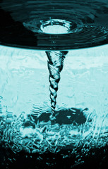 Vortex von überlaufendem Wasser im drehenden Glasrohr, Wasserglas mit rotierender Luftsäule, Wasserröhre mit blauem Strudel Sturm aus Luft, dekorative kinetische technische Skulptur.