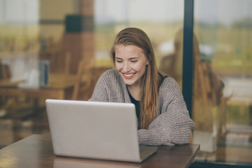 Successful female grapic designer watching tutorial about creative ideas at laptop computer during working process in office.Positive student with blonde hair reading business news on netbook