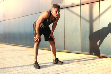 African man in sports clothing warming up outdoors, at sunset or sunrise.