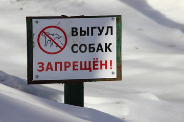 Dog walking is prohibited - the inscription in Russian in the city Park in winter against the snow