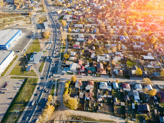 Fototapeta na wymiar Aerial view of a large number of small houses on the outskirts of the city on an autumn afternoon during Indian summer with the road and cars