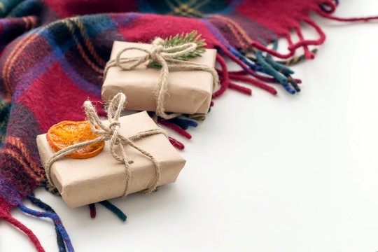 Christmas gifts in craft paper with fir branches, dried mandarin, anise and cone on the cozy plade. Copy space