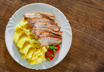 meat slices with mashed potatoes in white plate on wooden table background