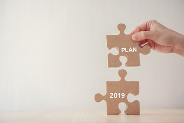 Hand of woman connecting jigsaw puzzle with new year planning 2019