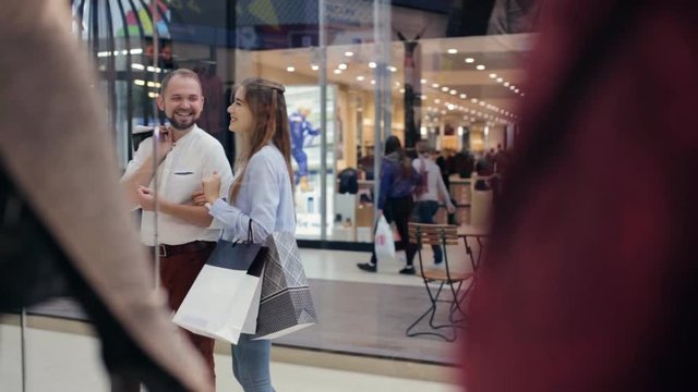 Couple in the mall standing in front of the shop window and talking