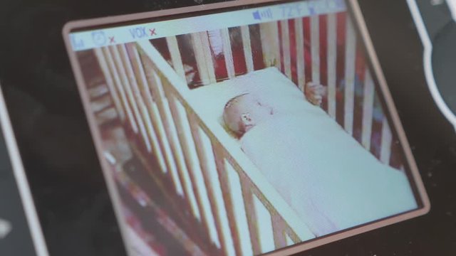 A Baby Monitor Showing A Brother Playing With His Baby Sister