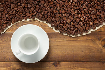 coffee beans and empty cup on wooden background