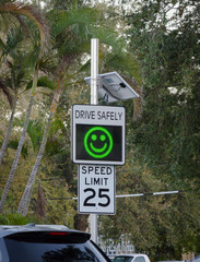 Speed limit 25 sign with electronic message board showing smiley face