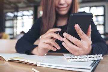 Closeup image of a beautiful asian woman holding , using and looking at smart phone while working in office