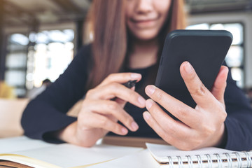 Closeup image of a beautiful asian woman holding , using and looking at smart phone while working in office