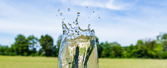 Spritzendes Wasser aus Glas auf Natur Hintergrund - Getränk