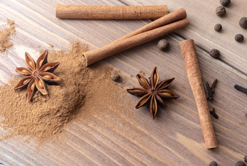 Cinnamon sticks, cinnamon powder, star anise and other spices closeup on wood
