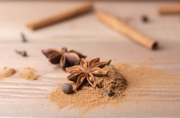 Cinnamon sticks, cinnamon powder, star anise closeup on wood