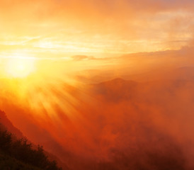 Landscape - sunset with mountain view, orange bright fog illuminated of sunlight with clouds in the sky