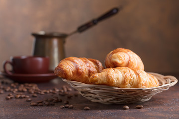 Fresh and tasty croissants  and cup of coffee on old copper background.