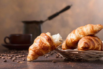 Fresh and tasty croissant  and cup of coffee on old copper background.