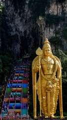 Golden statue of Lord Murugan and colorful stairs of Batu Caves, Malaysia