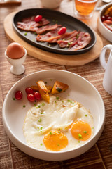 Breakfast with eggs, tomatoes , mushrooms, ham, bacon and herbs top view over the wooden table