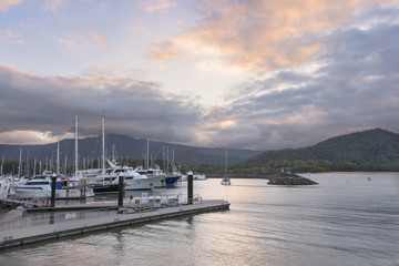 Sailboats in harbor at sunset with mountains in background