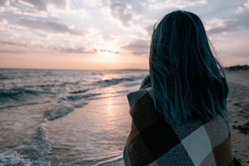 Woman enjoying view of sunset on sea coast.