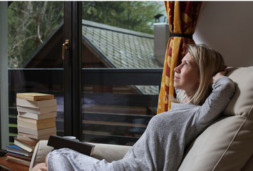 Looking for inspiration. Young beautiful pensive woman making some notes and looking through window