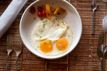 Breakfast with eggs, tomatoes , mushrooms, ham, bacon and herbs top view over the wooden table