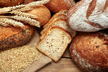 fresh baked whole and sliced bread on wooden background