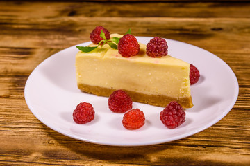 White plate with cheesecake New York, leaf of mint and raspberries on wooden table