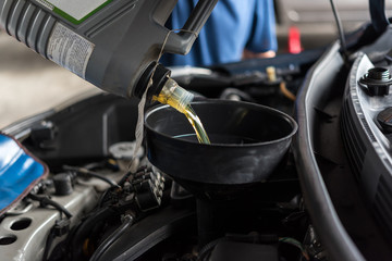 Car mechanic fills a fresh lubricant engine oil