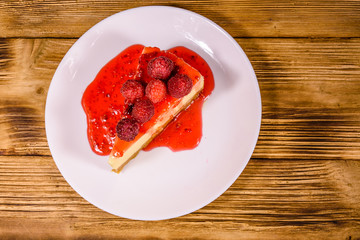 White plate with cheesecake New York and raspberries on wooden table. Top view