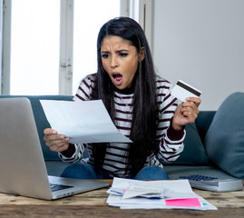 Unhappy stressed young female angry with credit card bill calculating home finance and paying bills