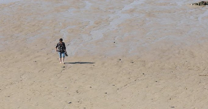 Woman wades walks beach Dover England English Channel. Near White Cliffs of Dover. Sandy ocean vacation destination in summer time. Warm vacation weather. Serene and peaceful.