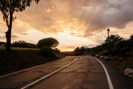 Empty asphalt curvy road against sunset golden sky, copy space