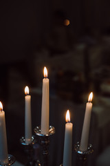 Burning candles on silver candlestick against dark background . Vintage style. 