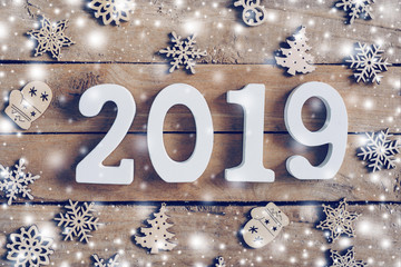 Wooden numbers forming the number 2019, For the new year and white snow with snowflakes on rustic wooden background.