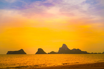 Naklejka na ściany i meble Beautiful sunset at sea beach with silhouette island background and twilight sky