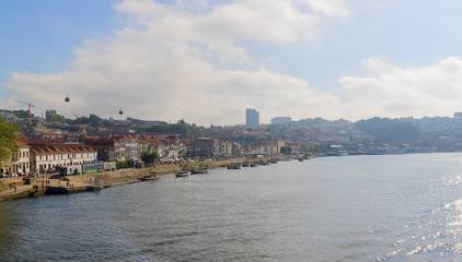 Obraz premium Scenic view of Vila Nova de Gaia from Dom Luis I Bridge in a sunlight. Porto, Portugal. The boats on the waterfront of the river Douro.