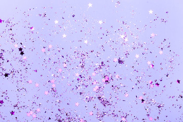 Violet confetti and violet stars and sparkles on violet background.