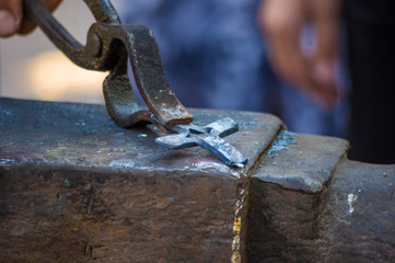 blacksmith performs the forging of hot glowing metal on the anvil