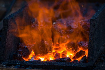 blacksmith furnace with burning coals, tools, and glowing hot metal workpieces